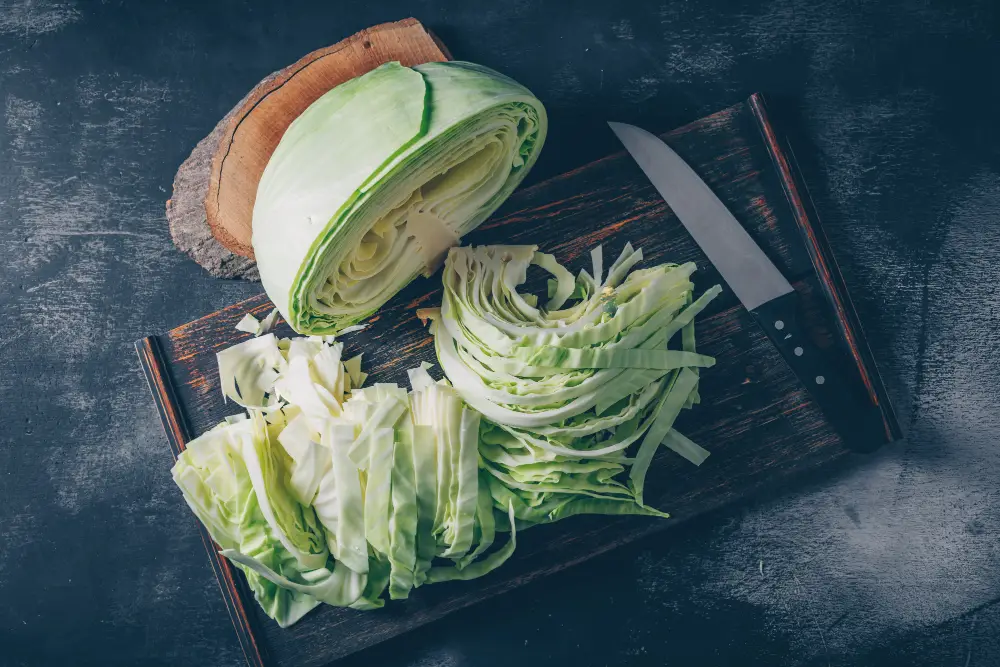 flat-lay-sliced-chopped-cabbage-cutting-board-knife-with-wood-stub-dark-textured-background-horizontal